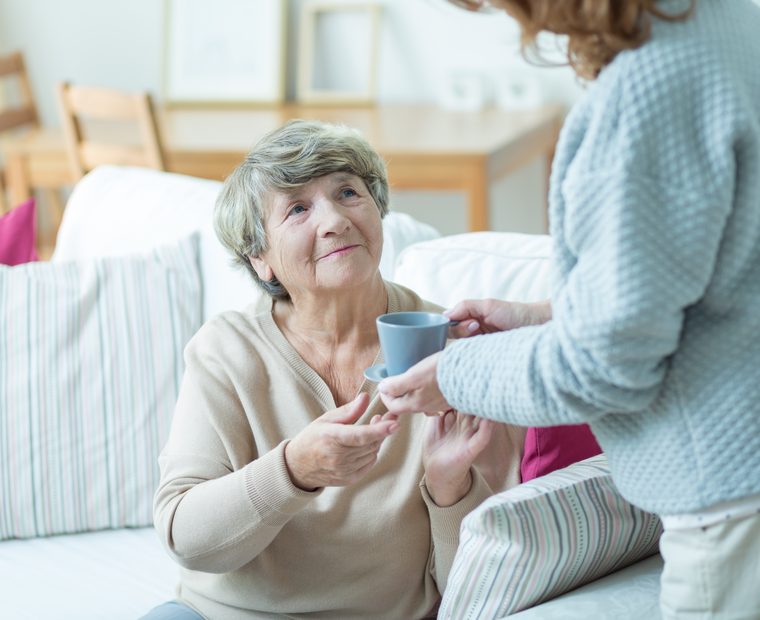 Betreuerin hilft einer Seniorin beim Aufstehen