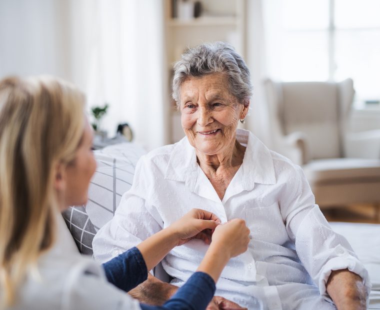Betreuerin am Bett einer Seniorin