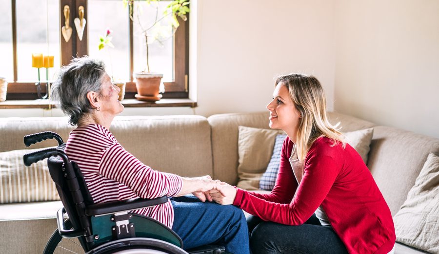 Betreuerin im Gespräch mit einer Seniorin im Rollstuhl