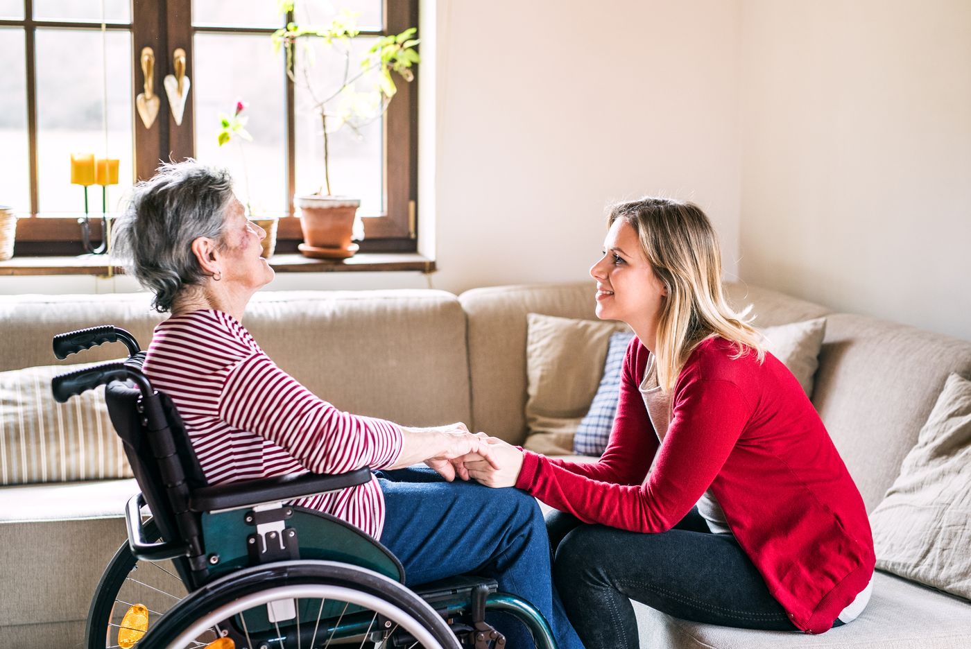 Betreuerin im Gespräch mit einer Seniorin im Rollstuhl
